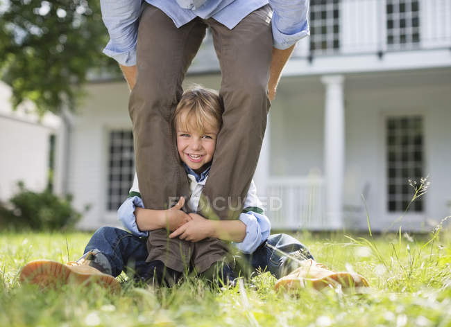 Boy peeking out from between father's legs — Stock Photo