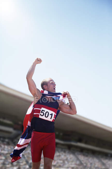 Track and field athlete cheering with British flag — Stock Photo