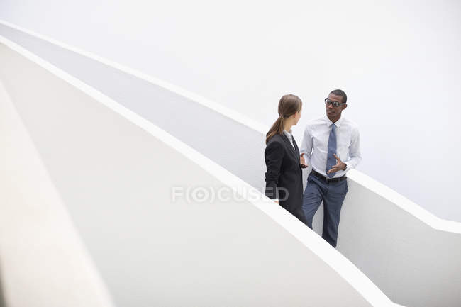 Бізнесмен і бізнес-леді говорять про сучасні сходи в сучасному офісі — стокове фото