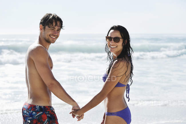 Portrait of happy couple holding hands on beach — Stock Photo
