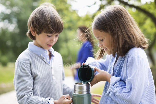 Les enfants versent le thé du thermos à l'extérieur — Photo de stock