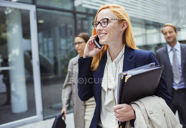 Femme d'affaires parlant sur un téléphone portable à l'extérieur de l'immeuble de bureaux — Photo de stock