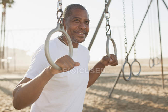 Älterer Mann mit Trainingsringen am Strand — Stockfoto