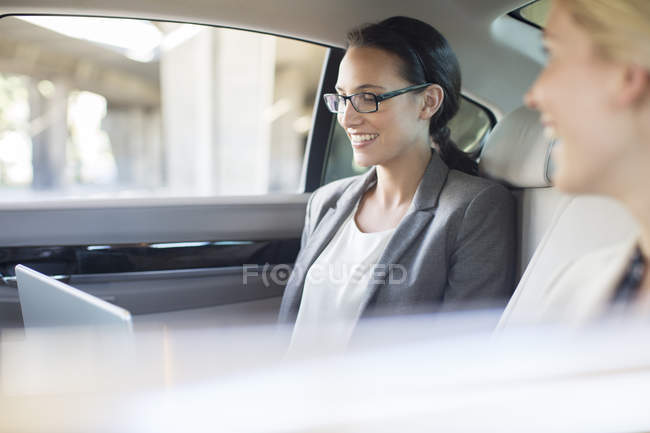 Businesswomen working in car back seat — Stock Photo