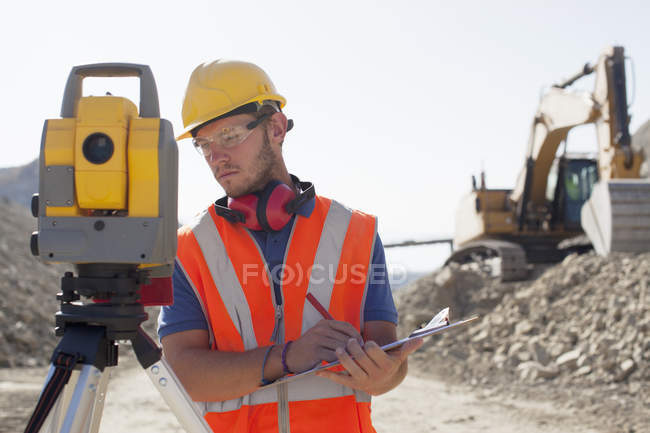 Worker using leveling equipment in quarry — Stock Photo