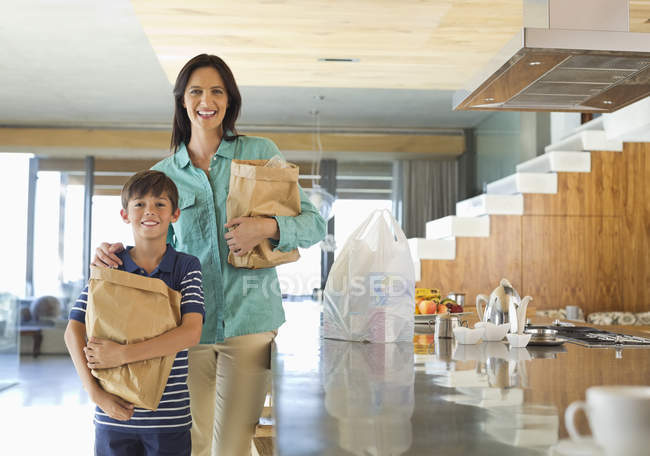 Madre e hijo sosteniendo alimentos en la cocina - foto de stock