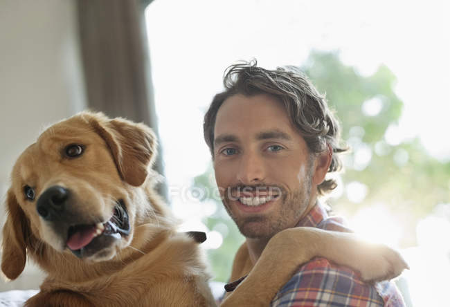 Uomo sorridente cane da accarezzamento in casa — Foto stock
