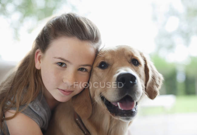 Closeup view of girl hugging dog indoors — Stock Photo
