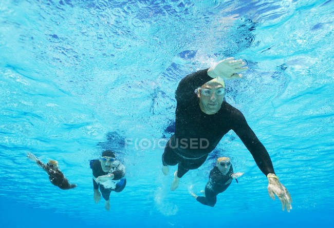Уверенные и сильные триатлонисты в гидрокостюмах под водой — стоковое фото