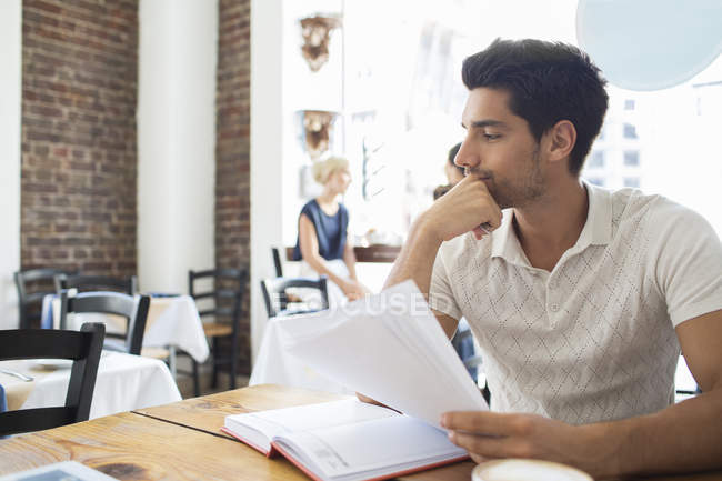 Geschäftsmann schaut sich Dokumente im Café an — Stockfoto