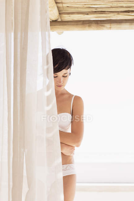 Femme en soutien-gorge et sous-vêtements derrière le rideau — Photo de stock