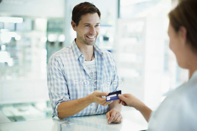 Mann bezahlt mit Kreditkarte in Drogerie — Stockfoto