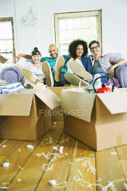 Jóvenes amigos relajarse en un nuevo hogar - foto de stock