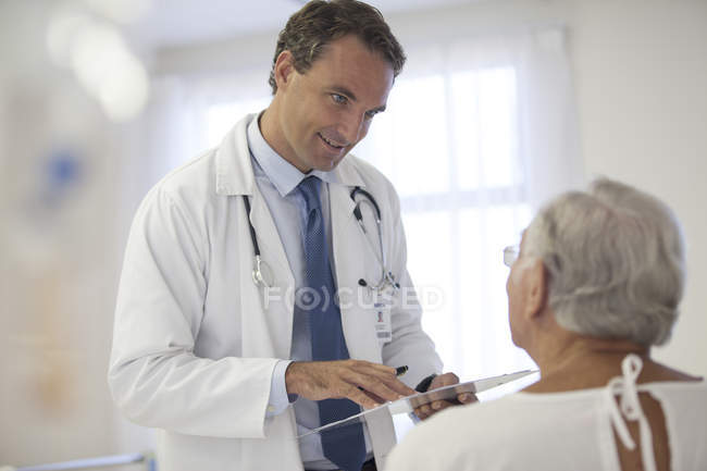 Médico hablando con paciente mayor en el hospital - foto de stock