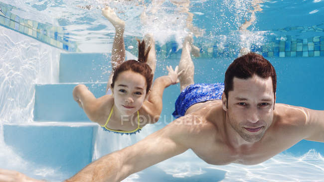 Отец и дочь плавают в бассейне — стоковое фото