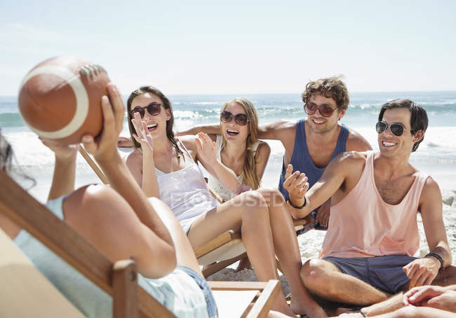 Happy friends with football hanging out at beach — Stock Photo