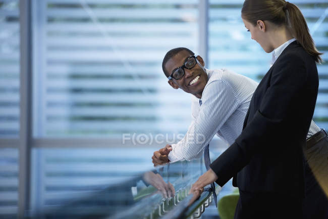 Smiling businessman and businesswoman talking at modern office — Stock Photo
