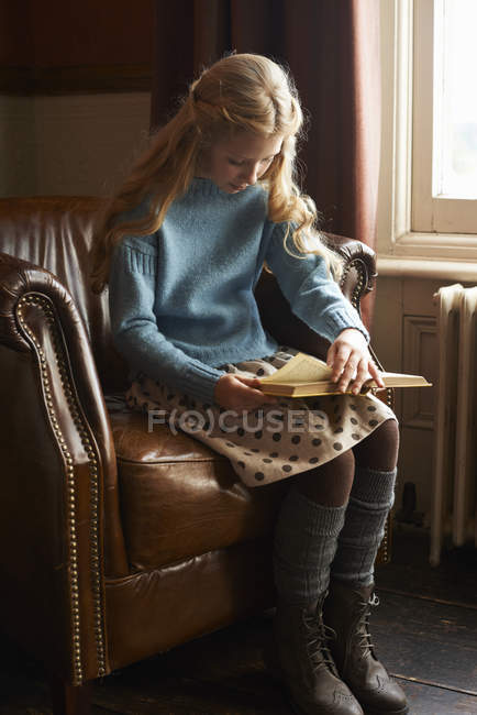 Mädchen liest Buch im Sessel — Stockfoto
