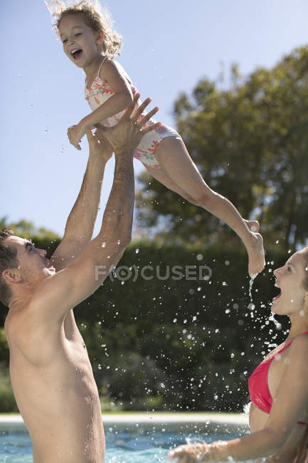 Família feliz brincando na piscina — Fotografia de Stock