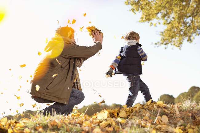 Padre e figlio giocano in foglie autunnali — Foto stock