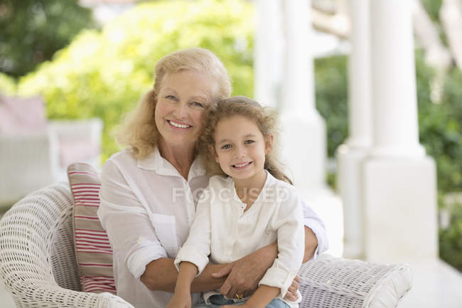 Older woman and granddaughter smiling on porch — Stock Photo