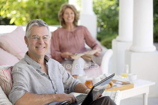 Старший білий чоловік використовує ноутбук на патіо — стокове фото