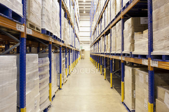 Pilhas de caixas no corredor no armazém — Fotografia de Stock