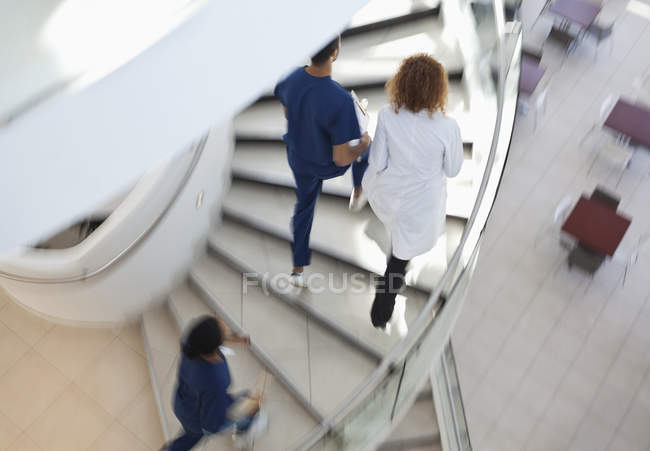 Personal del hospital escalando escalones espirales - foto de stock