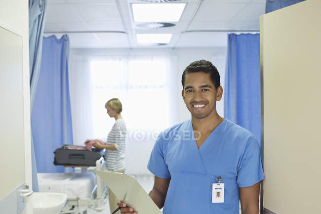 Enfermera sujetando portapapeles en la habitación del hospital - foto de stock