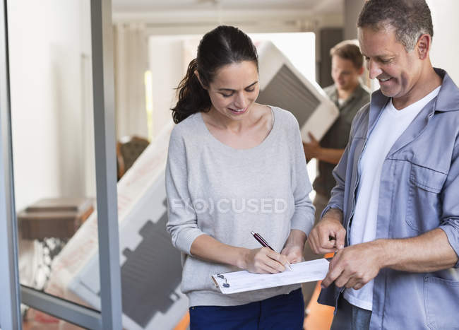 Young woman signing for package at home — Stock Photo