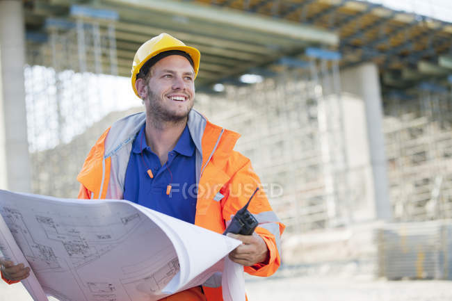 Worker reading blueprints on site — Stock Photo