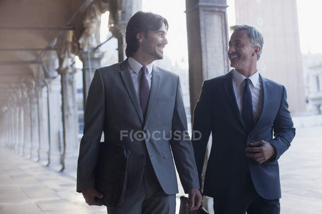 Uomo d'affari sorridente che cammina lungo il corridoio — Foto stock