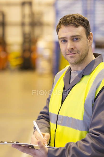Worker using clipboard in warehouse — Stock Photo