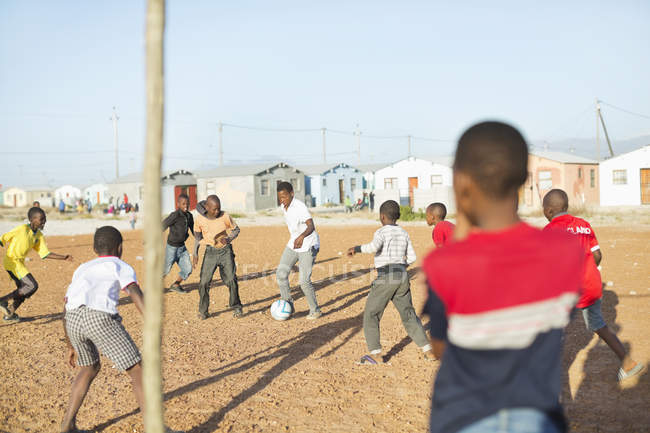 Meninos africanos jogando futebol juntos no campo de sujeira — Fotografia de Stock