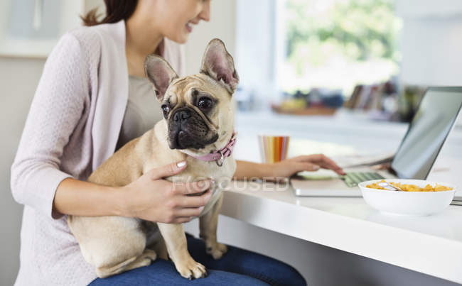 Woman using laptop with dog on lap — Stock Photo