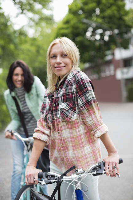 Women standing on bicycles on city street — Stock Photo