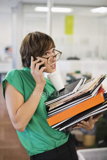 Деловая женщина с папками разговаривает по мобильному телефону — стоковое фото