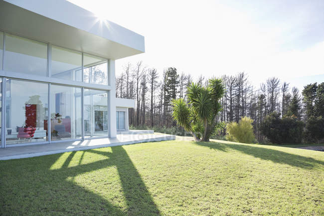 Сучасний будинок, що кидає тіні на доглянутий газон — стокове фото