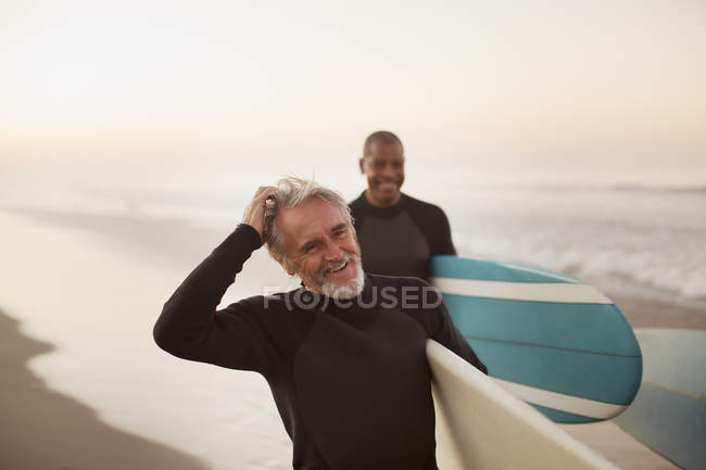 Ältere Surfer tragen Bretter am Strand — Stockfoto