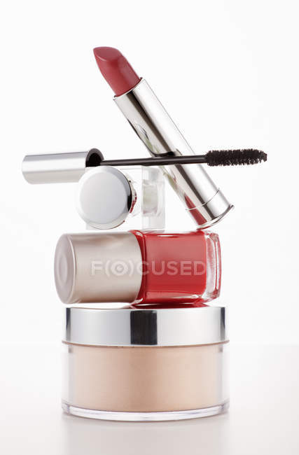 Rouge à lèvres, mascara et vernis à ongles empilés sur un pot hydratant — Photo de stock