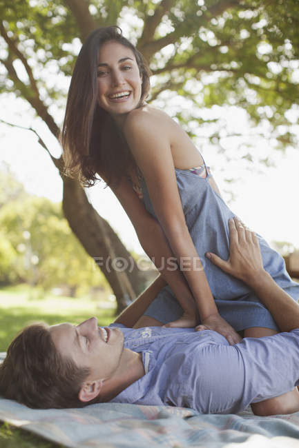 Retrato de pareja sonriente sobre manta en hierba - foto de stock