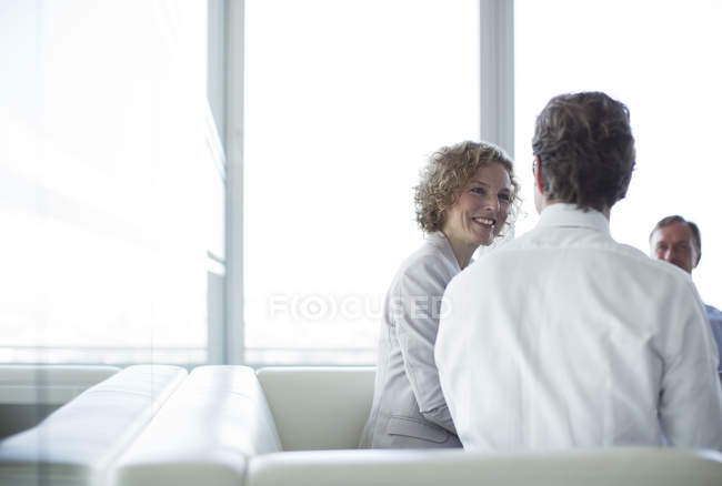 Business people sitting on sofa in office lobby — Stock Photo