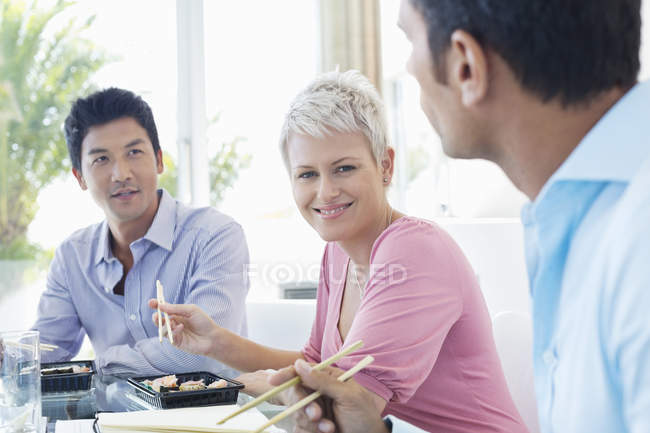 Business people eating sushi at modern office — Stock Photo