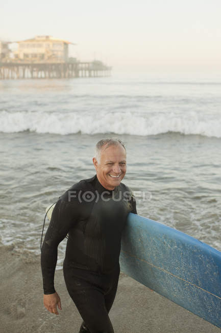 Mayores surfistas llevando tabla en la playa - foto de stock