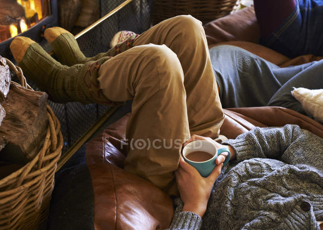 Boy drinking cup of coffee by fire — Stock Photo