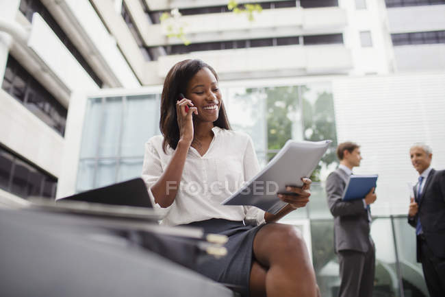 Femme d'affaires parlant sur un téléphone portable en regardant des documents — Photo de stock