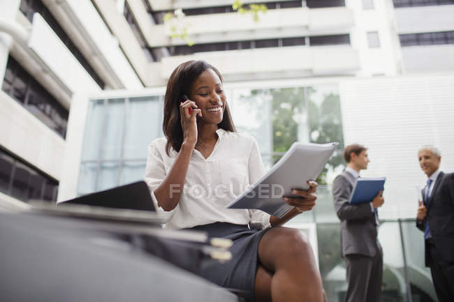 Donna d'affari che parla al cellulare guardando i documenti — Foto stock