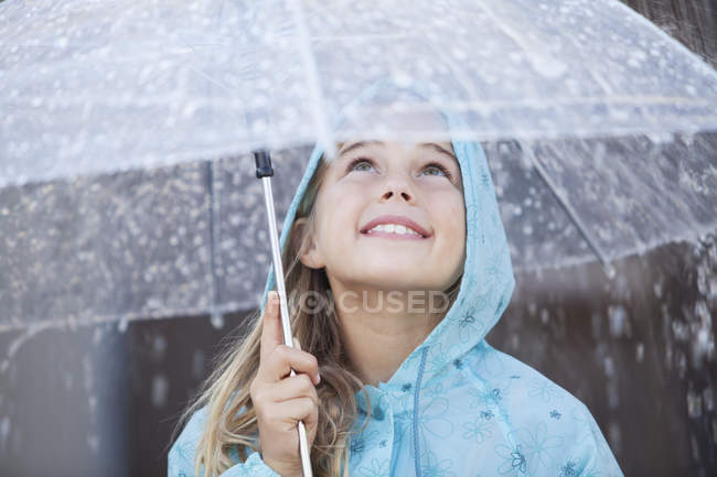 Primer plano de niña sonriente bajo el paraguas en el aguacero - foto de stock