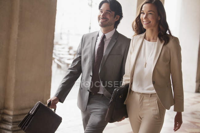 Hombre de negocios sonriente y mujer de negocios caminando - foto de stock