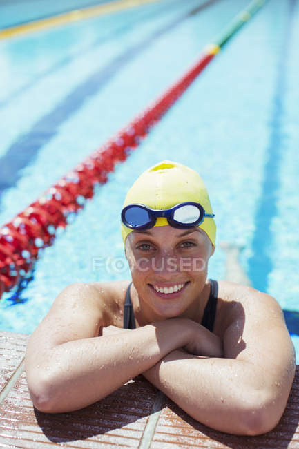 Porträt einer lächelnden Schwimmerin, die sich am Beckenrand lehnt — Stockfoto